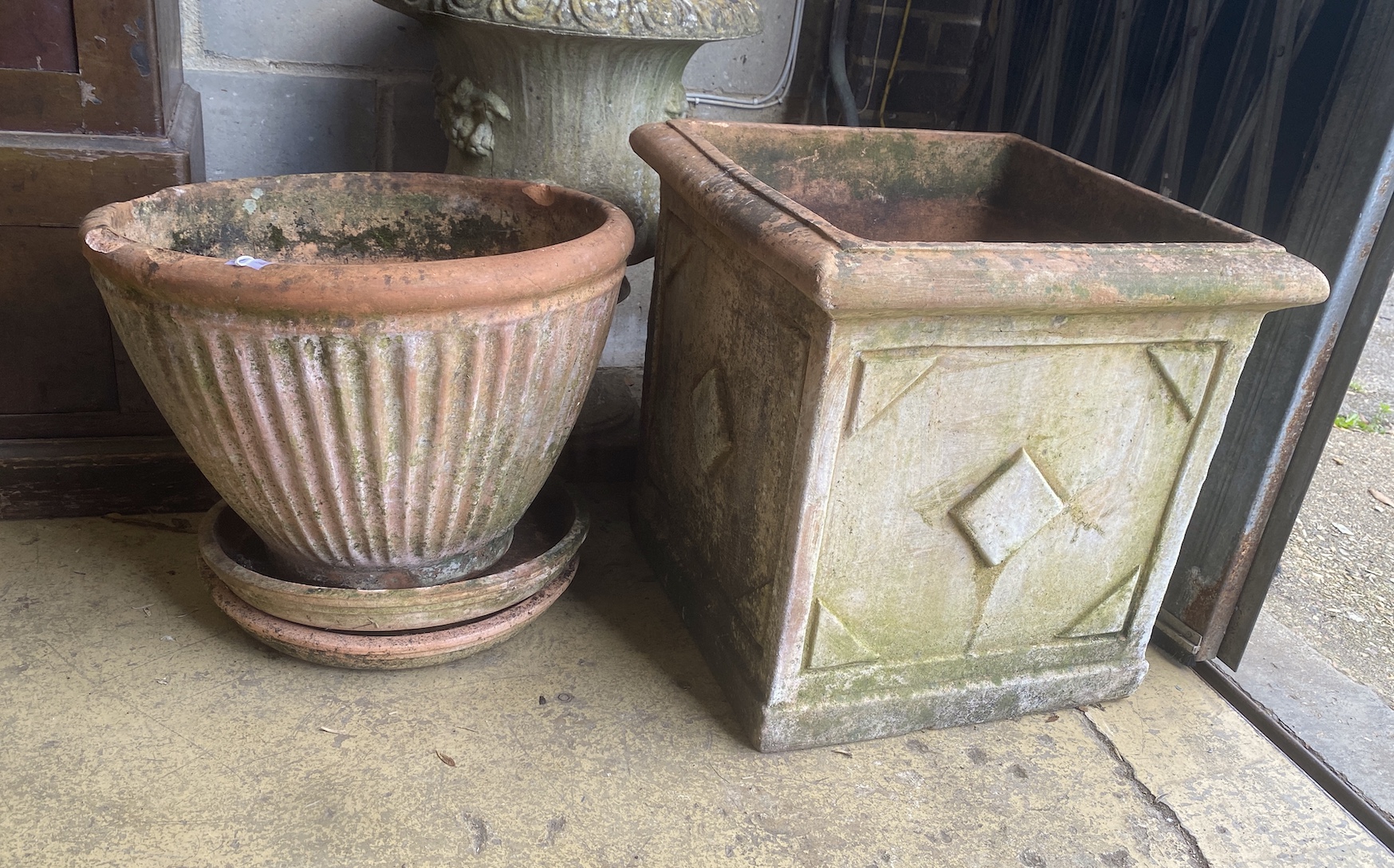 A square weathered terracotta garden planter, width 52cm, height 50cm together with a circular terracotta planter and two circular tray bases